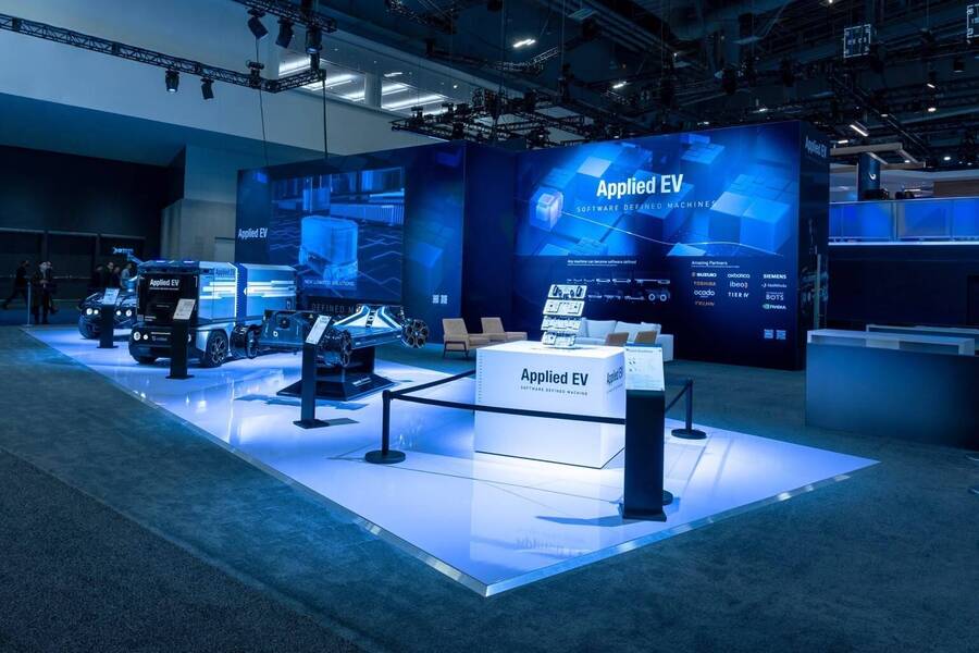 Applied EV vehicles on a lit platform in front of an LED wall at CES 2023