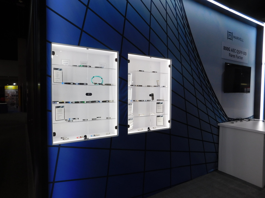 Glass-front display cases on a dark wall in Marvell's OFC booth
